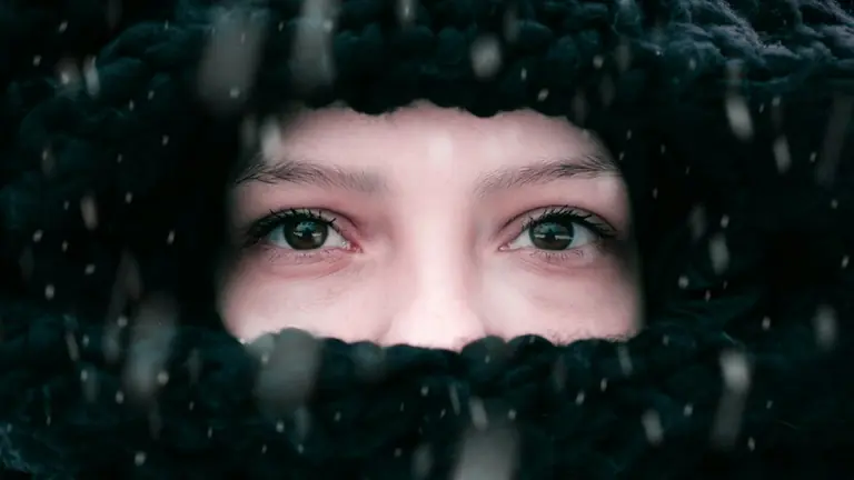 a woman's eyes are covered by a black blanket