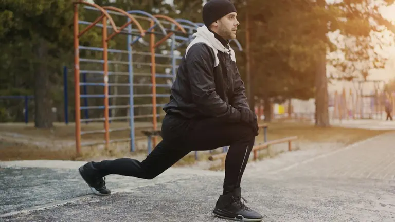 Man stretching outdoors in winter clothing.