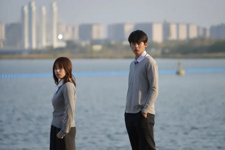Young couple standing by a waterfront with cityscape in Zhengzhou, China.