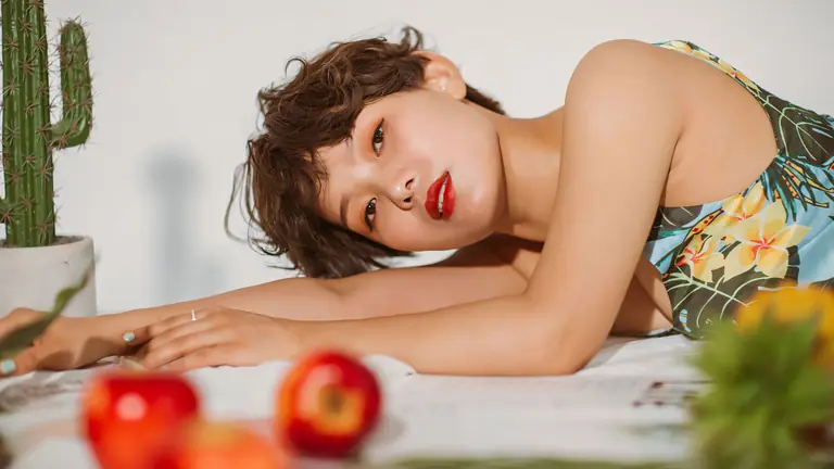 Portrait of a young woman lying near apples and a cactus, exuding a fresh and vibrant vibe.