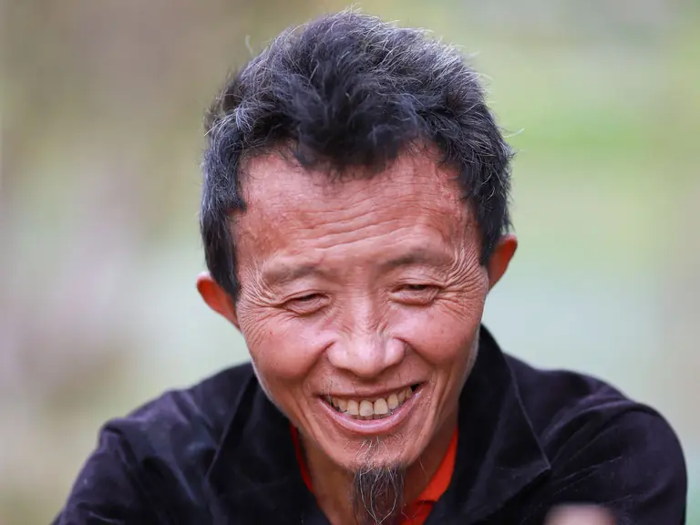Capture a joyful moment with a smiling man outdoors in Lào Cai, Vietnam, showcasing traditional attire.