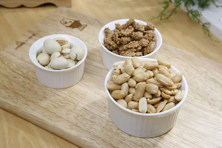 Close-up of various nuts in bowls on a wooden chopping board, perfect for food presentations.