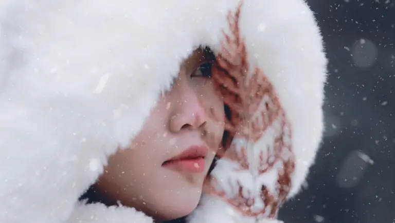 Close-up portrait of a woman in a fur hood during snowfall.