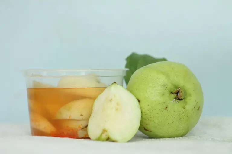 a glass of apple cider next to a green apple