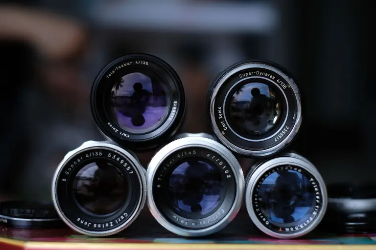Artistic close-up shot of vintage Carl Zeiss camera lenses stacked creatively.