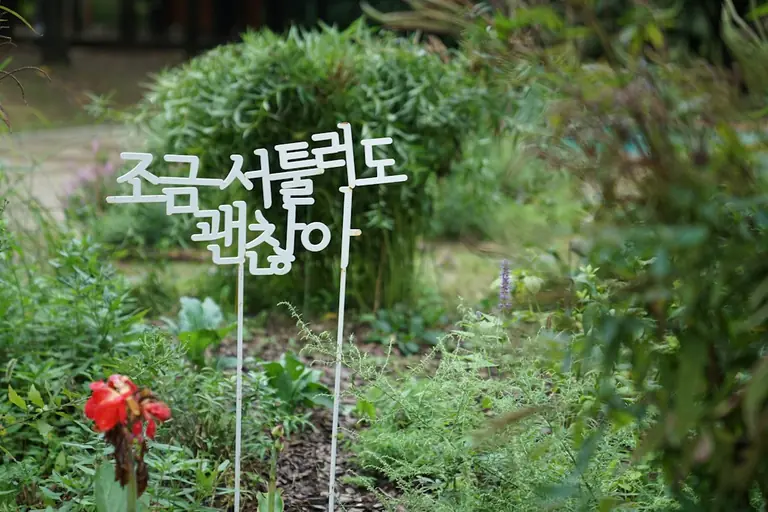 a sign that is in the grass near a flower