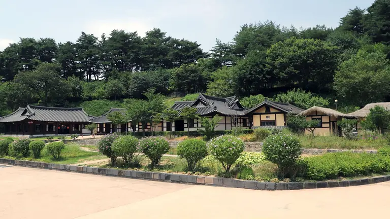 Scenic view of traditional Korean village with Hanok houses surrounded by lush greenery.