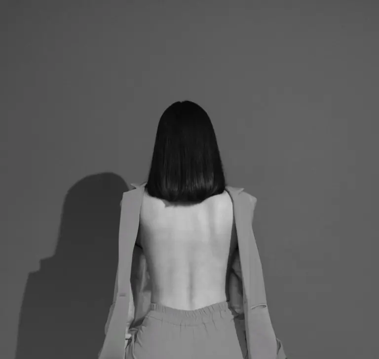 Elegant monochrome fashion portrait featuring a backless design and shadow play.