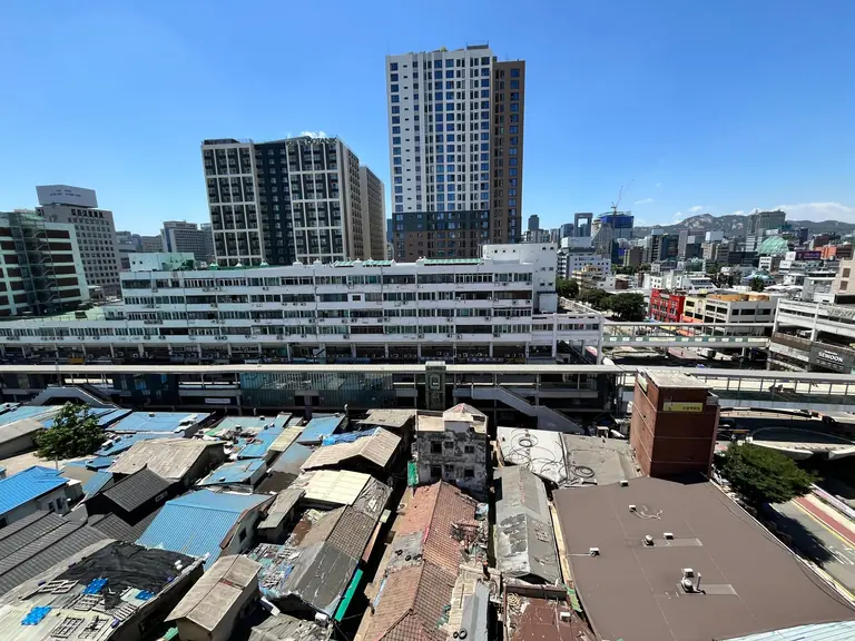 Aerial view of city skyline blending modern skyscrapers and older architecture under a clear blue sky.