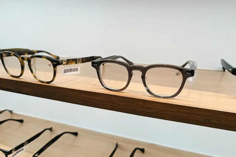 Minimalist display of modern eyewear on a wooden shelf in a well-lit setting.