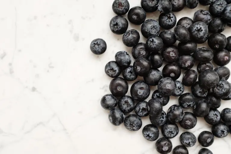 A close-up of fresh organic blueberries scattered on a marble surface, perfect for healthy eating.