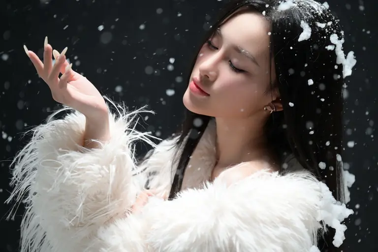 Stunning portrait of a woman in a white coat with snowflakes, capturing winter elegance.