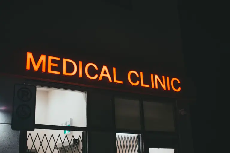 Bright neon medical clinic signage at night, creating a vivid street scene.