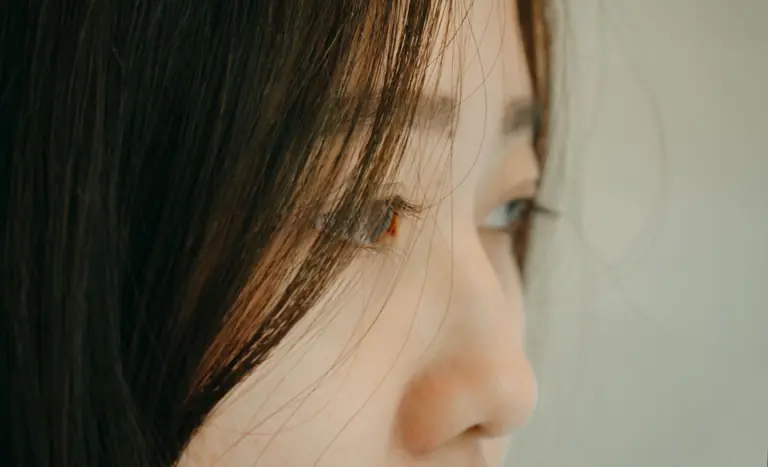 A serene close-up of a woman's face, showing delicate features and soft lighting.