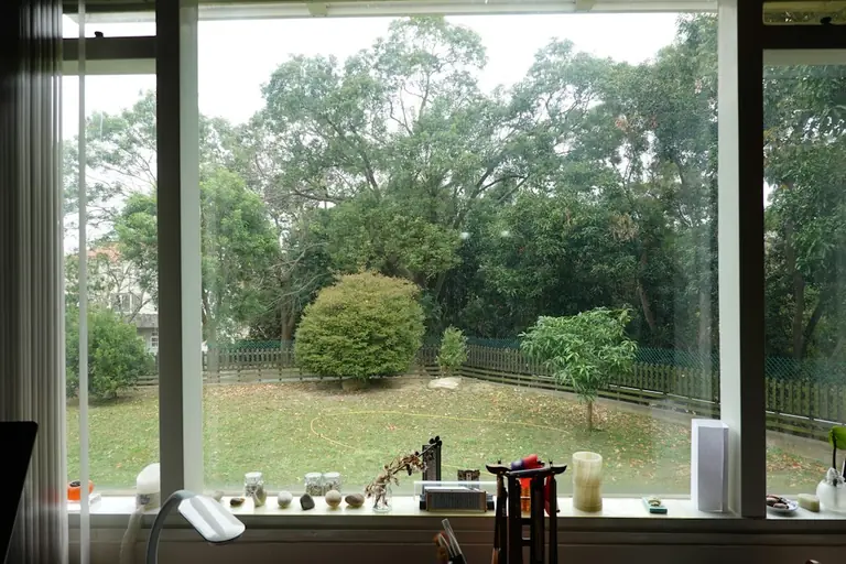 A kitchen window with a view of a yard