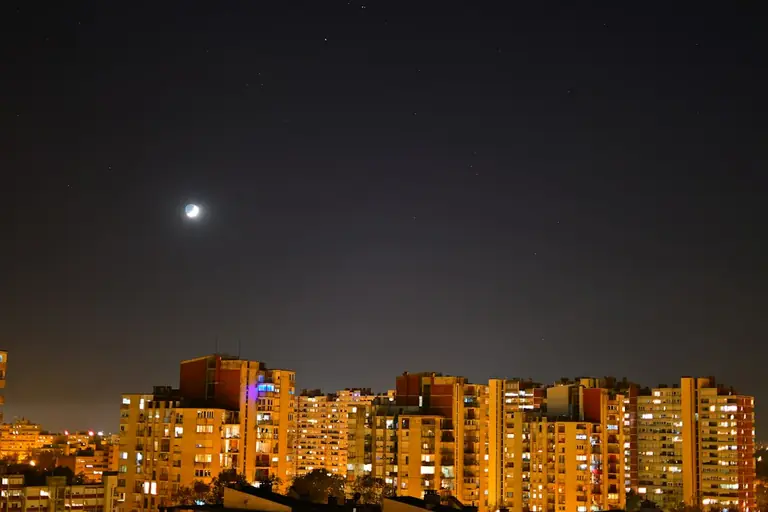 a city at night with the moon in the sky