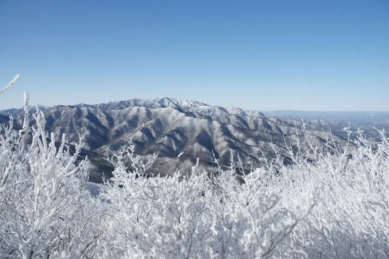 Scenic view of a snow-covered mountain range under a clear blue sky, captured in winter.