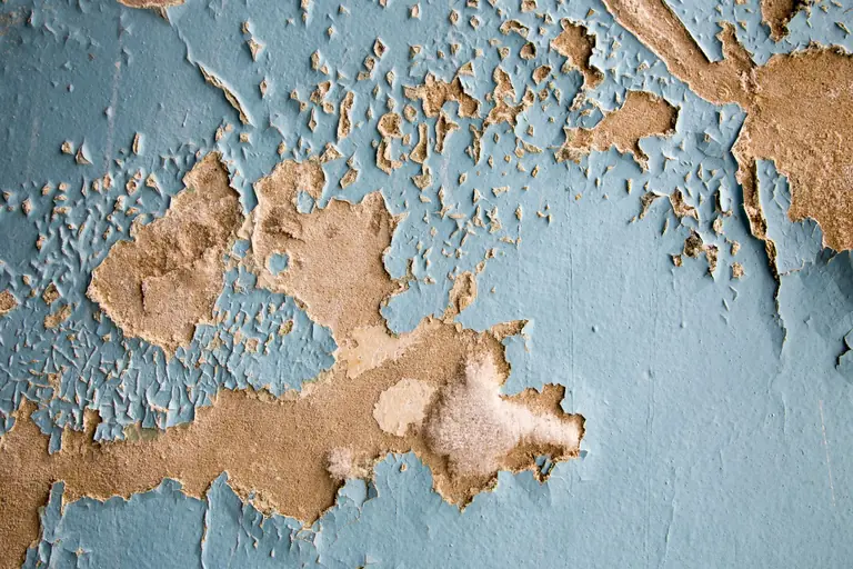 Detailed texture of cracked and peeling blue paint on an old wall surface. Perfect for background.