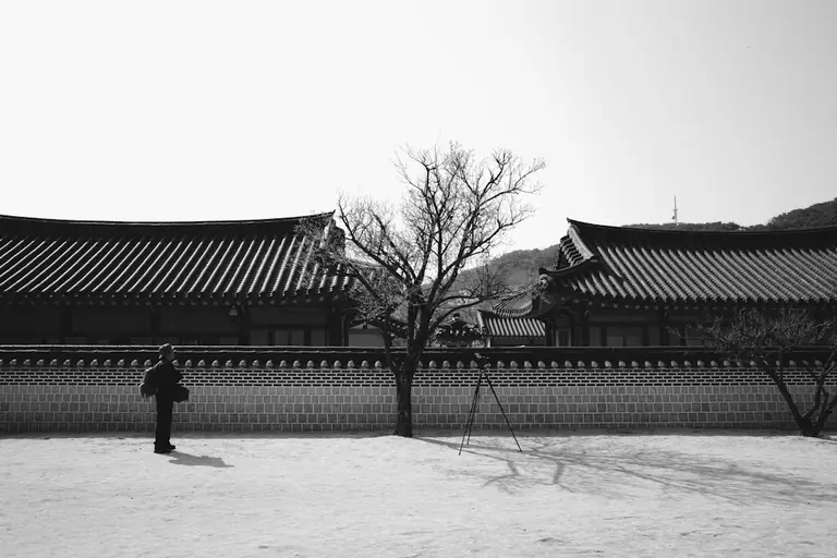 A black and white photo of a person standing in front of a building